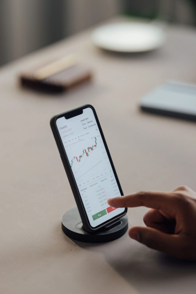 Cryptocurrency Trading: Hands of a Businessman on Mobile Phone at Desk